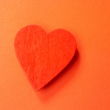 Un cœur en papier rouge sur un fond orange. Une vie sociale riche et heureuse le bonheur du cerveau.